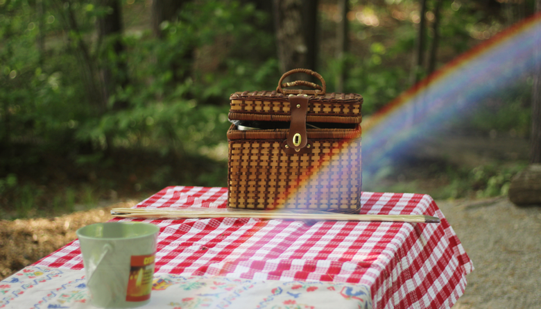 Korg på ett bord ute i skogen med en kaffekopp.