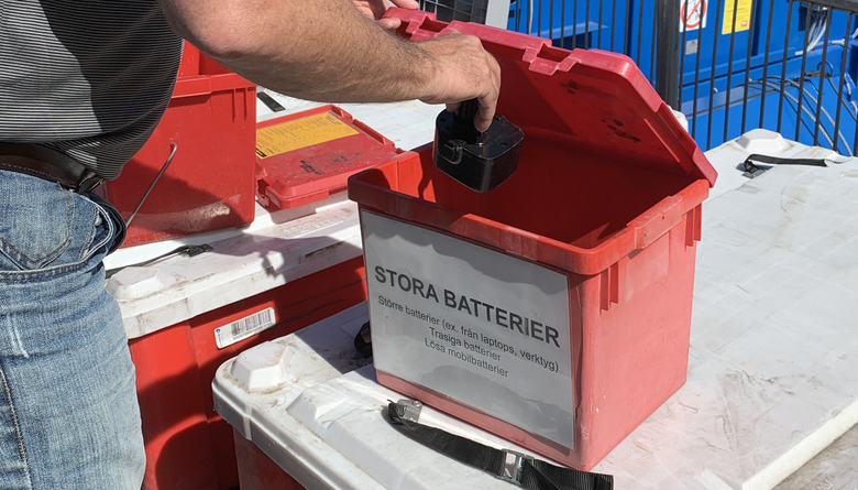 Besökare slänger batteri i en röd box. 